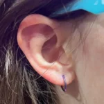 Children's ear piercing service at Titan Piercing. A professional piercer gently working on a young girl's ear with a sterile and safe piercing procedure, ensuring a comfortable experience for kids.