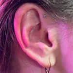 Forward helix piercing at Titan Piercing Montreal.   The image features a forward helix piercing positioned on the outer rim of the ear, near the face, showcasing the studio's expertise in creating stylish and precise ear piercings.