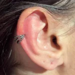 Helix piercing at Titan Piercing. The image features a helix piercing on the upper ear cartilage, adorned with a stylish earring, highlighting the studio's expertise in creating precise and fashionable ear piercings.