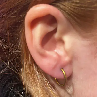 Earlobe piercing at Titan Piercing Montreal. The image displays a single earlobe piercing adorned with a stylish earring, highlighting the studio's precision and expertise in performing fashionable ear piercings.